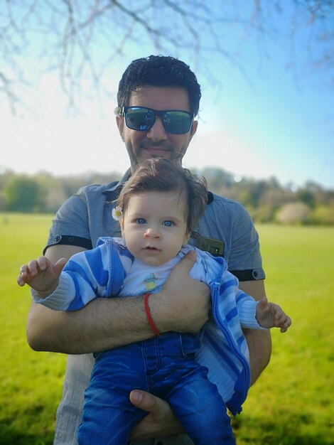 Foto retrato de un padre sosteniendo a su hijo mientras está de pie al aire libre