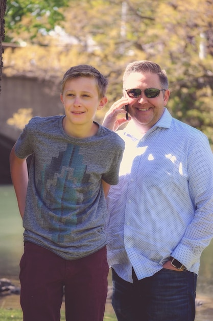 Foto retrato de un padre con su hijo de pie en un parque