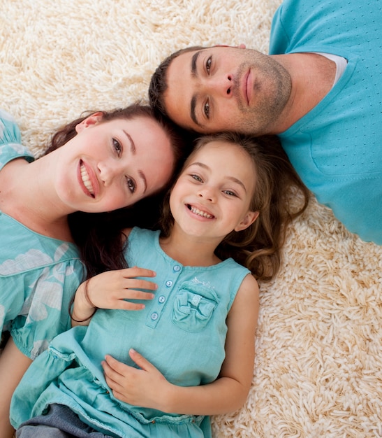 Retrato de padres e hija en el piso con las cabezas juntas