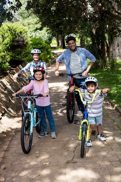 Retrato de padres e hijos de pie con bicicleta en el parque