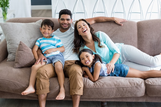 Retrato de padres e hijos sentados en el sofá de la sala de estar