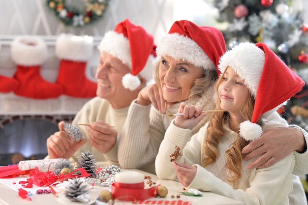 Retrato de padres felices con nieto preparándose para la Navidad juntos