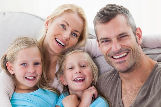 Retrato de padres y gemelos que se sientan en un sofá