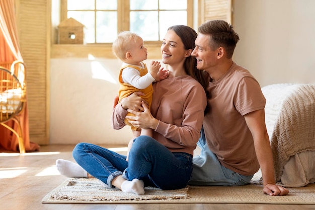 Retrato de padres jóvenes felices divirtiéndose con su hijo pequeño en casa