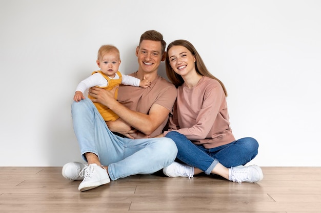 Foto retrato de padres con un lindo niño sentado en el suelo en casa