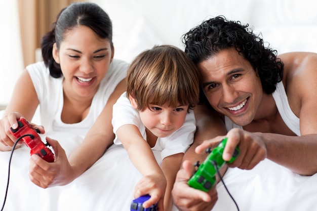 Retrato de padres sonrientes jugando videojuegos con su hijo