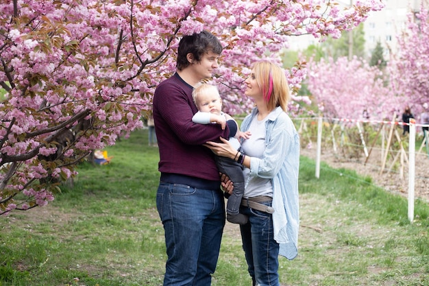 Retrato de padres con su hijo en la primavera cerca de la cereza japonesa sakura se encuentra con la primavera Sakura florece muy bellamente con flores rosas