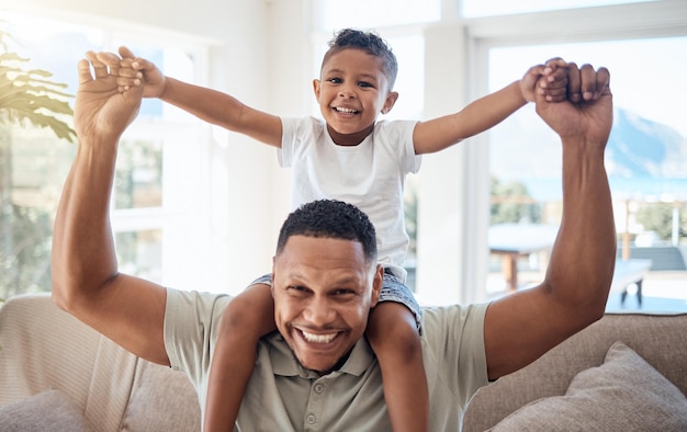 Retrato pai e filho no ombro sorriem e felizes sendo amorosos e brincalhões juntos no salão Amor pai negro e menino com felicidade passam tempo de qualidade e alegres na sala de estar