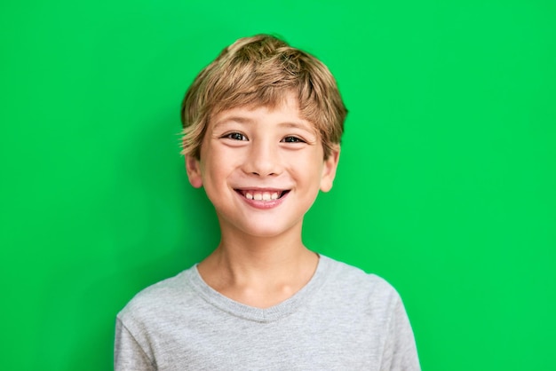 Retrato pantalla verde y niño con una maqueta de sonrisa y niño confiado contra un fondo de estudio Enfrente a un niño varón y a una persona joven con felicidad relajada e informal con un desarrollo feliz y alegre
