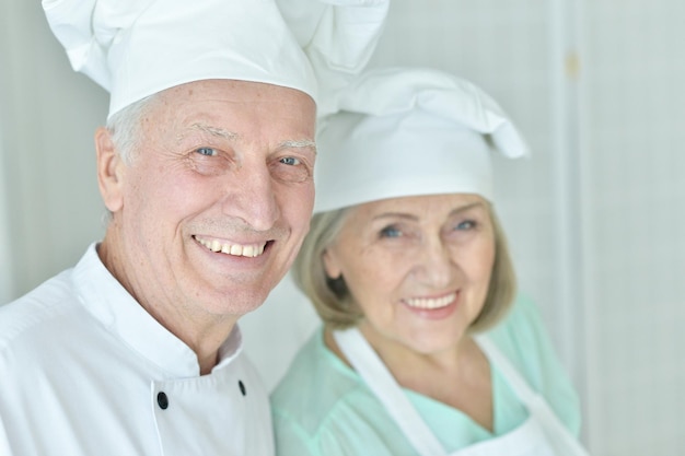 Retrato de un par de chefs senior sonrientes en la cocina