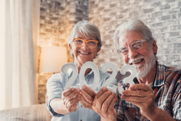 Retrato de un par de dos ancianos jubilados que mantienen juntos los números de 2023 en casa Primer plano de los números de año nuevo celebrando y metas para el nuevo concepto de vida