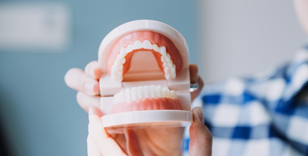 Retrato parcial do conceito de estomatologia de menina com dentes brancos fortes olhando para a câmera e dedos sorridentes perto do rosto Closeup de jovem no estúdio do dentista dentro de casa