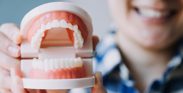 Retrato parcial do conceito de estomatologia de menina com dentes brancos fortes olhando para a câmera e dedos sorridentes perto do rosto Closeup de jovem no estúdio do dentista dentro de casa
