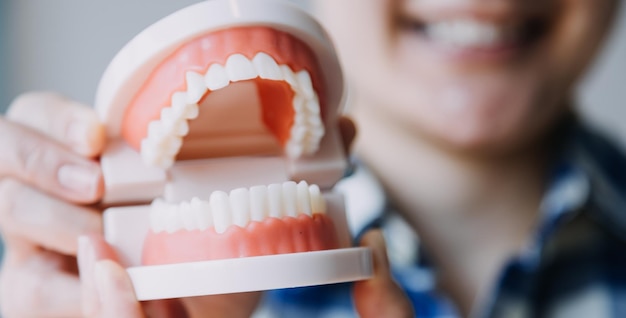 Retrato parcial do conceito de estomatologia de menina com dentes brancos fortes olhando para a câmera e dedos sorridentes perto do rosto Closeup de jovem no estúdio do dentista dentro de casa