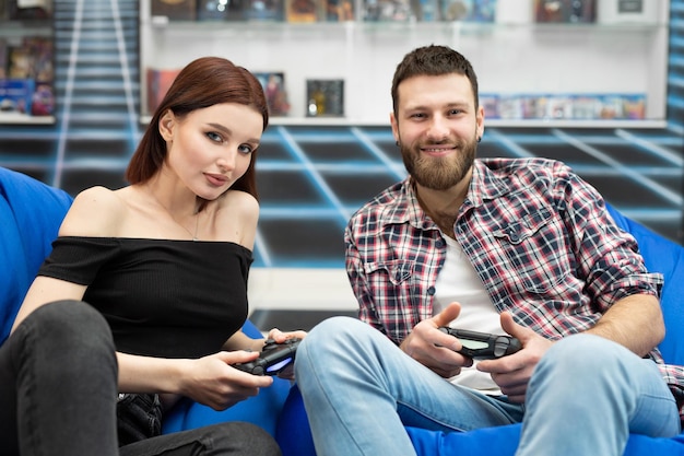 Retrato de una pareja activa y divertida que disfruta jugando videojuegos con un gamepad de consola en sus manos.
