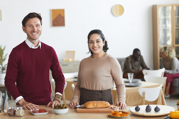 Retrato de pareja adulta feliz y sonriendo mientras cocina para la cena en el interior,