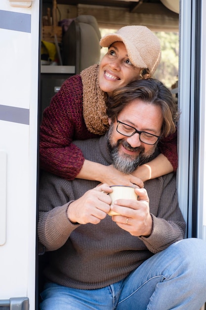 Retrato de una pareja adulta de hombre y mujer sentada en la puerta de una autocaravana y disfrutando de las vacaciones de viaje