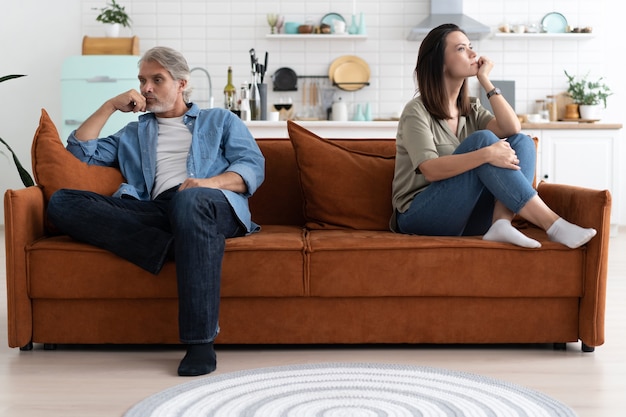 Retrato de una pareja adulta media sentada en el sofá después de la pelea.