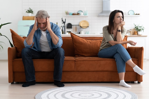 Retrato de una pareja adulta media sentada en el sofá después de la pelea.