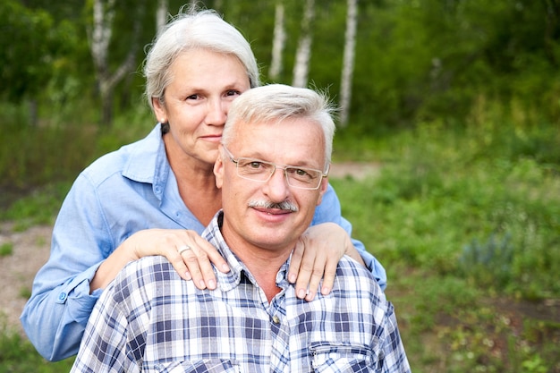 retrato, de, pareja anciana, enamorado, sonriente, y, abrazar, con, el telón de fondo, de, árboles verdes