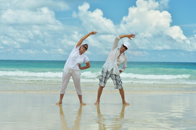 Retrato de una pareja de ancianos en una playa tropical haciendo ejercicio