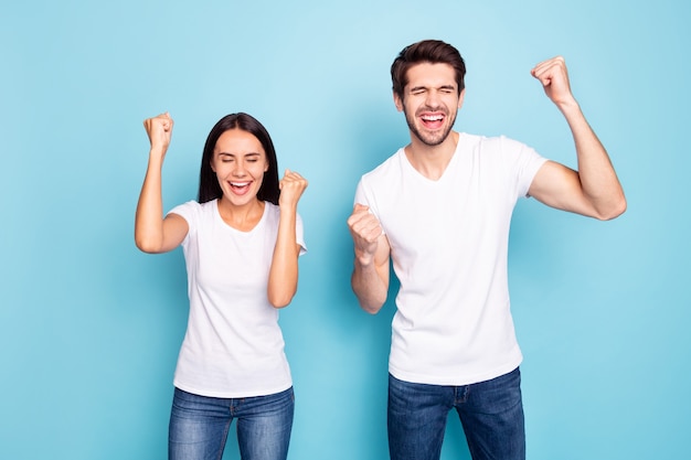 Retrato de pareja celebrando levantar puños boca abierta