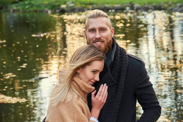 Retrato de pareja en la cita. Hombre barbudo pelirrojo abrazando a una linda mujer rubia en un parque de otoño.