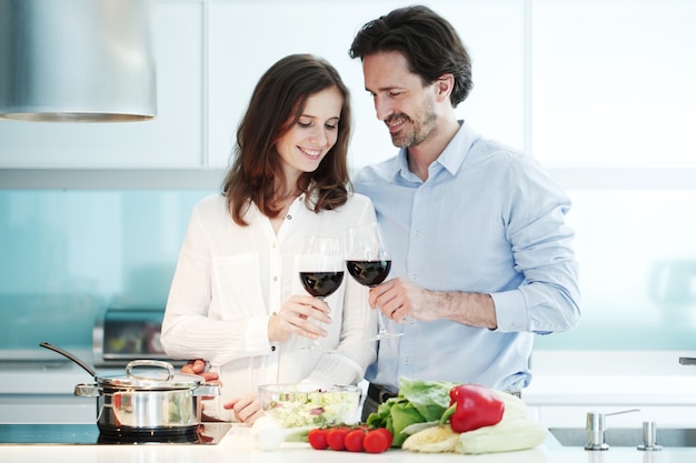 Retrato de una pareja con una copa de vino tinto mientras se cocina la cena