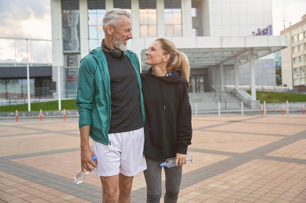 Retrato de pareja deportiva de mediana edad activa en ropa deportiva mirando el uno al otro caminando juntos