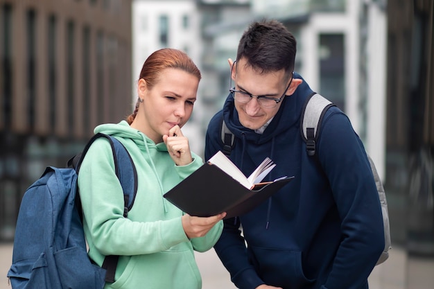 Retrato de pareja de dos hermosos estudiantes universitarios felices al aire libre en el campus