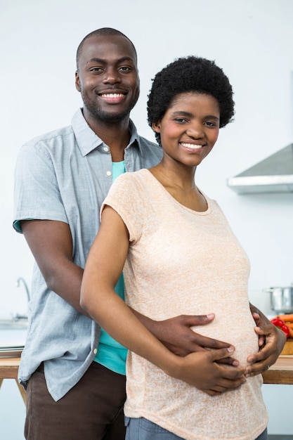 Retrato de pareja embarazada abrazándose en la cocina en casa