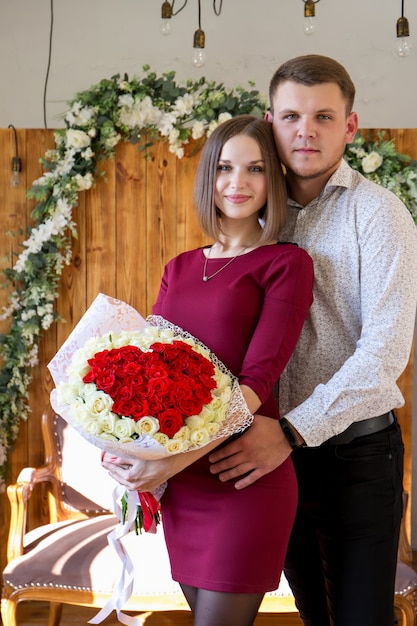 Retrato de una pareja enamorada de un gran ramo de rosas