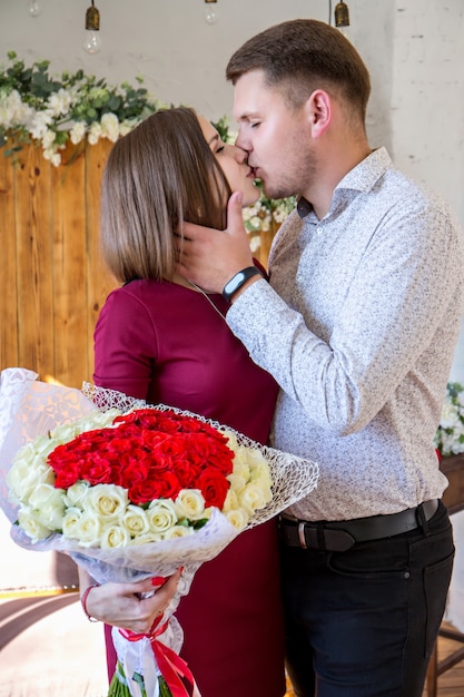 Foto retrato de una pareja enamorada de un gran ramo de rosas