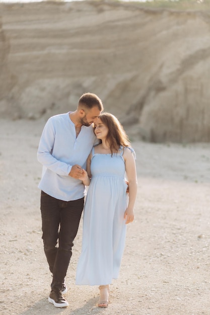 Retrato de una pareja encantadora de pie juntos en el campo verde Feliz pareja esperando un concepto de familia joven bebé