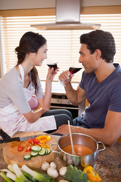 Retrato de una pareja encantadora con un vaso de vino mientras se cocina