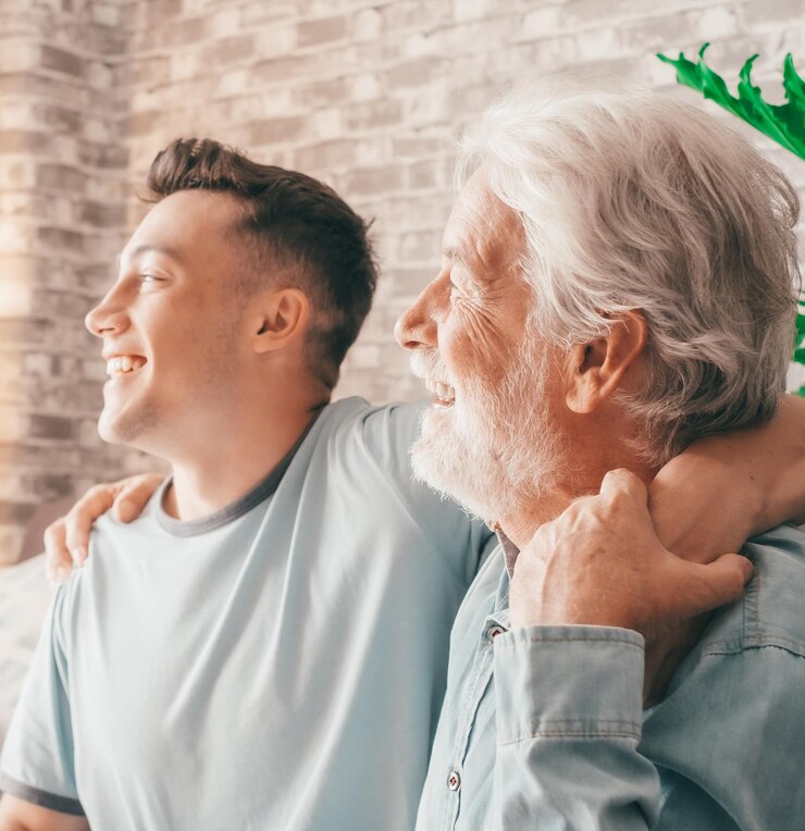Retrato de una pareja familiar, un joven zoomer y su viejo abuelo sonriendo mirando hacia el lado mientras están sentados.