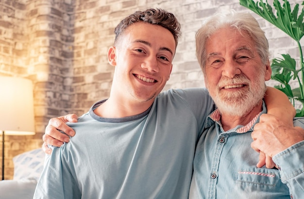 Foto retrato de una pareja familiar, un niño y su anciano abuelo sonriendo mirando a la cámara mientras se sientan en el sofá de casa de la vieja y nueva generación cuidando a las personas que amamos