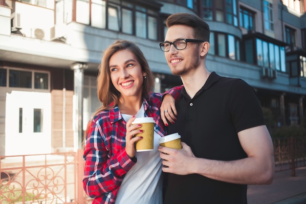 Retrato de pareja feliz caminar por la calle con café