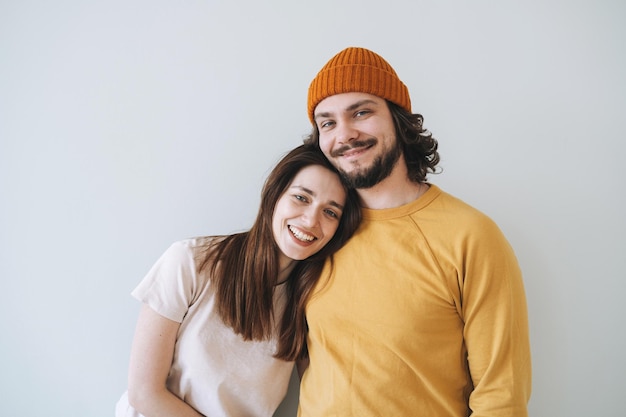 Retrato de una pareja feliz familia joven riéndose contra la pared gris