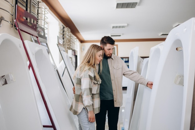 Retrato de una pareja feliz parada cerca de un baño nuevo en la tienda moderna