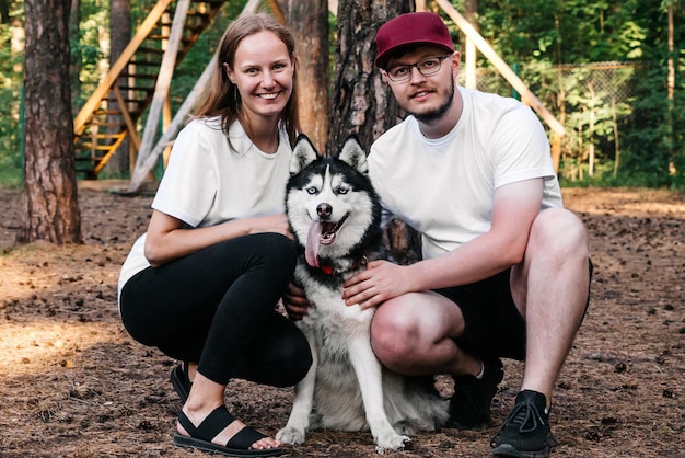 Retrato de una pareja feliz con un perro sentado en un campo de entrenamiento