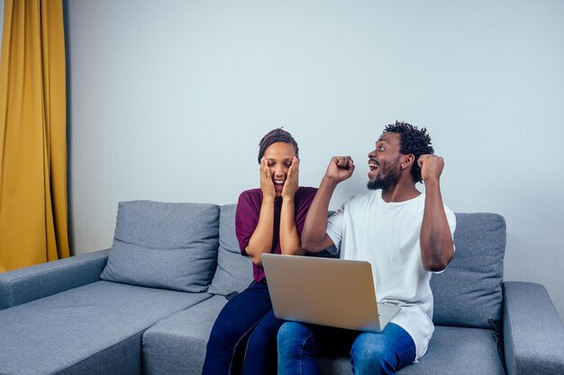 Retrato de una pareja feliz usando una computadora portátil en su casa