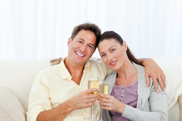 Retrato de una pareja con flautas de champán en el sofá