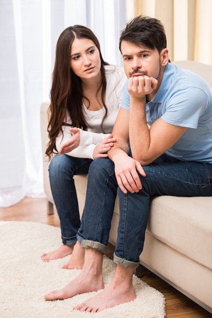 Retrato de pareja frustrada están sentados en el sofá.