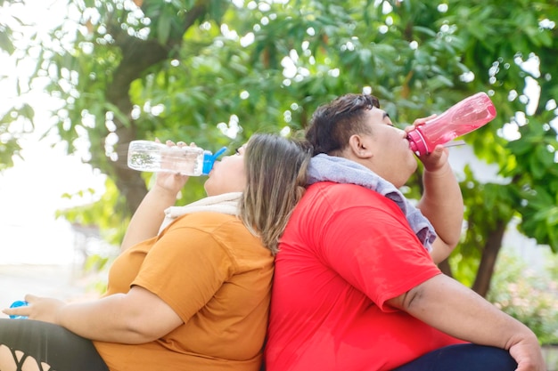 Retrato de pareja gorda resoplando agua en el parque