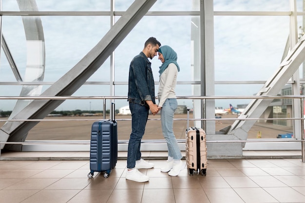 Retrato de una pareja islámica amorosa que se une en el aeropuerto mientras espera el vuelo