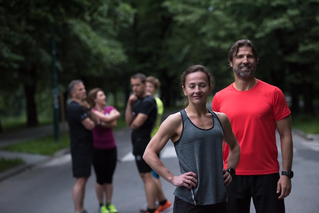 Foto retrato de una pareja de jogging saludable con el resto de su equipo de corredores en el fondo