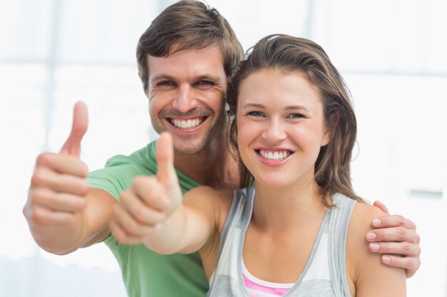 Foto retrato de una pareja joven apta gesticular pulgares arriba