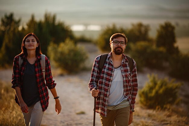 Retrato de una pareja joven feliz divirtiéndose en su viaje de senderismo Pareja de excursionistas caucásicos y asiáticos divirtiéndose en las vacaciones de verano