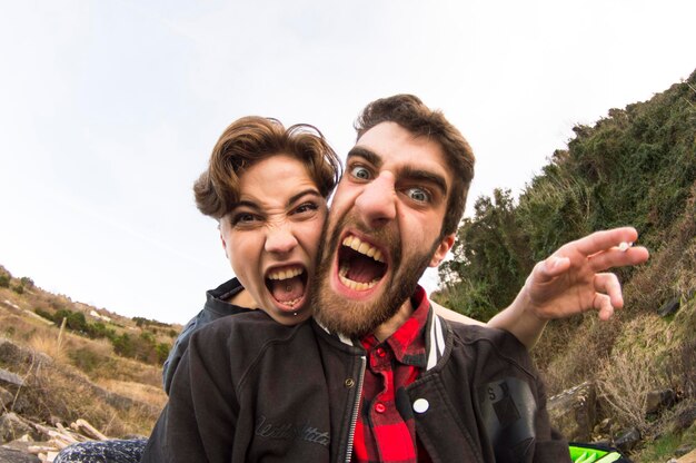 Foto retrato de una pareja joven gritando contra un cielo despejado